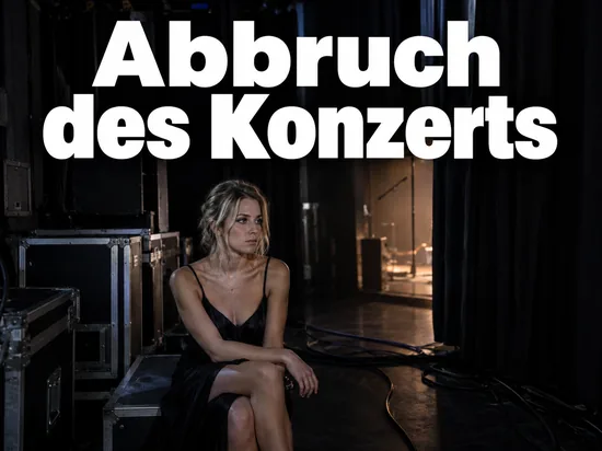 Frau sitzt backstage auf einer Transportkiste neben dem Bühnenvorhang