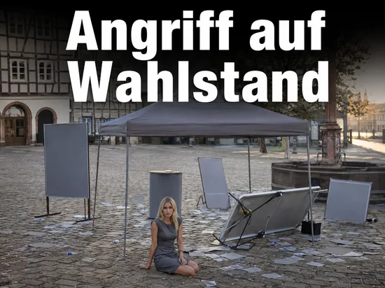 Frau sitzt vor einem verwuesteten Wahlkampfstand auf einem Marktplatz
