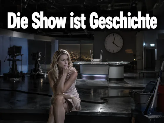 Frau sitzt nach Sendeschluss in einem dunklen Fernsehstudio unter einer Studiouhr