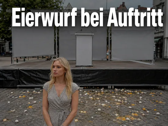 Frau steht vor einer Buehne auf einem Marktplatz mit zerbrochenen Eiern auf dem Pflaster