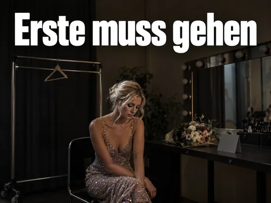 Frau in Abendkleid in einer leeren Kuenstlergarderobe am Schminktisch