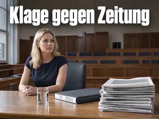Frau in dunklem Kleid sitzt an einem Tisch in einem leeren Gerichtssaal, daneben ein Stapel Zeitungen und ein Aktenordner