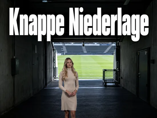 Blick aus dem Spielertunnel auf den Rasen eines Stadions, eine Frau steht im Tunnel
