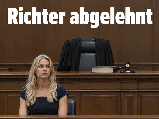 Frau sitzt vor einem leeren Richterpult, ueber der Stuhllehne haengt eine schwarze Robe