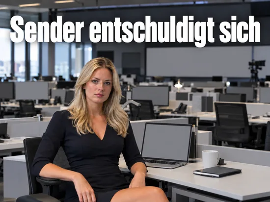Frau sitzt an einem Schreibtisch in einem großen Redaktionsraum mit Laptop