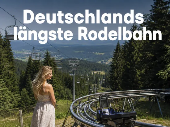 Frau an einer Sommerrodelbahn im Schwarzwald mit Sessellift, Schriftzug Deutschlands laengste Rodelbahn