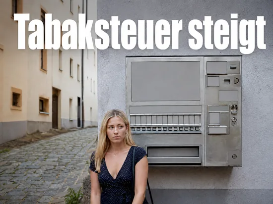 Frau steht in einer Gasse vor einem Zigarettenautomaten
