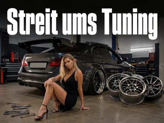 Tiefergelegtes Auto mit Heckspoiler in einer Werkstatt neben Alufelgen