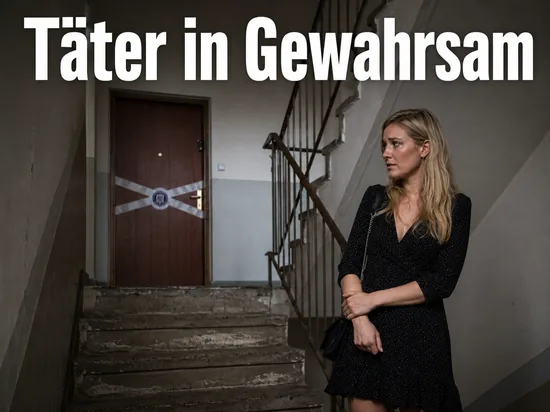 Frau in einem Treppenhaus vor einer versiegelten Wohnungstuer: Tatverdaechtiger in Gewahrsam