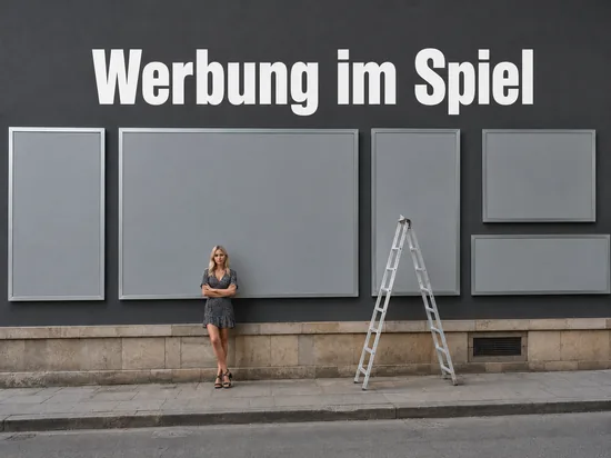 Hauswand mit mehreren leeren grauen Werbetafeln und einer Leiter